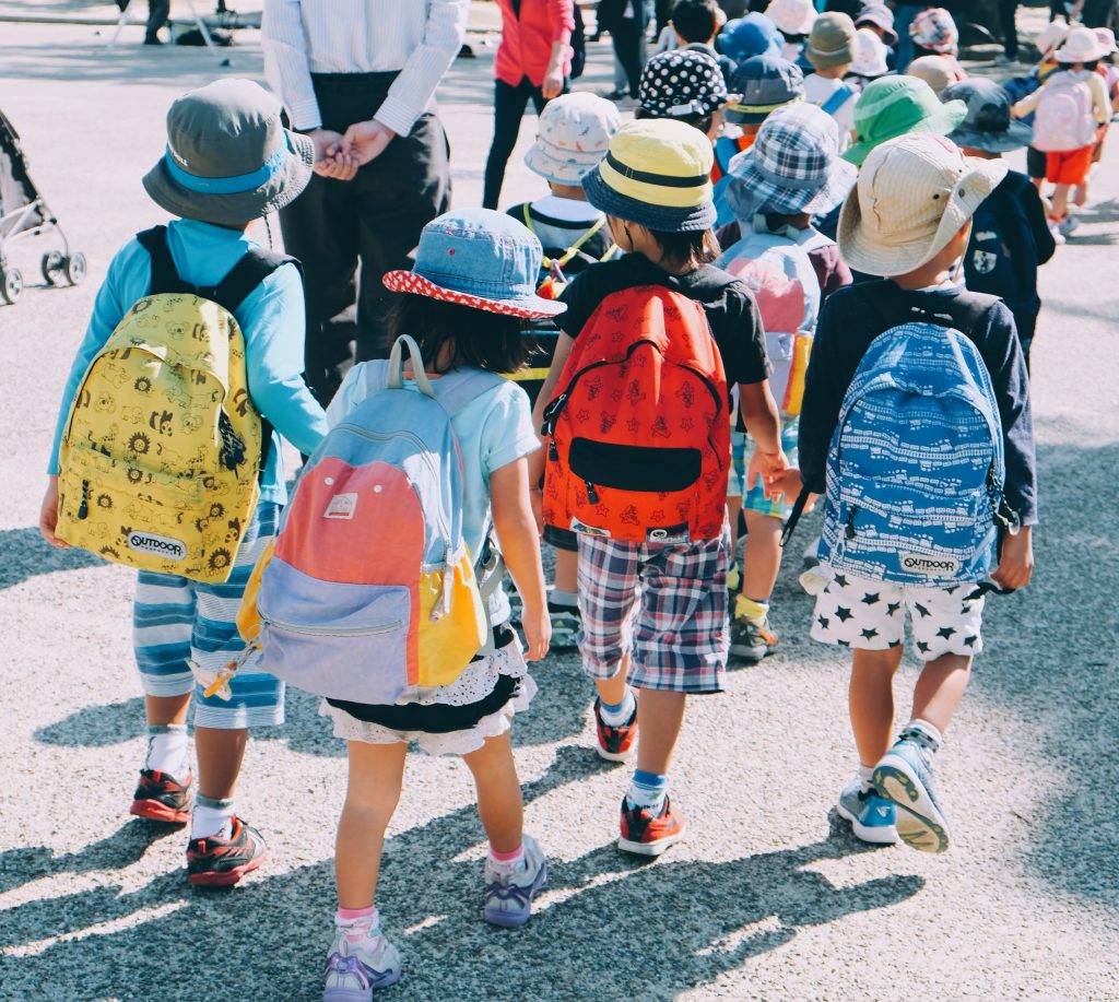 Fila de niños acudiendo al colegio, equipados con una mochila